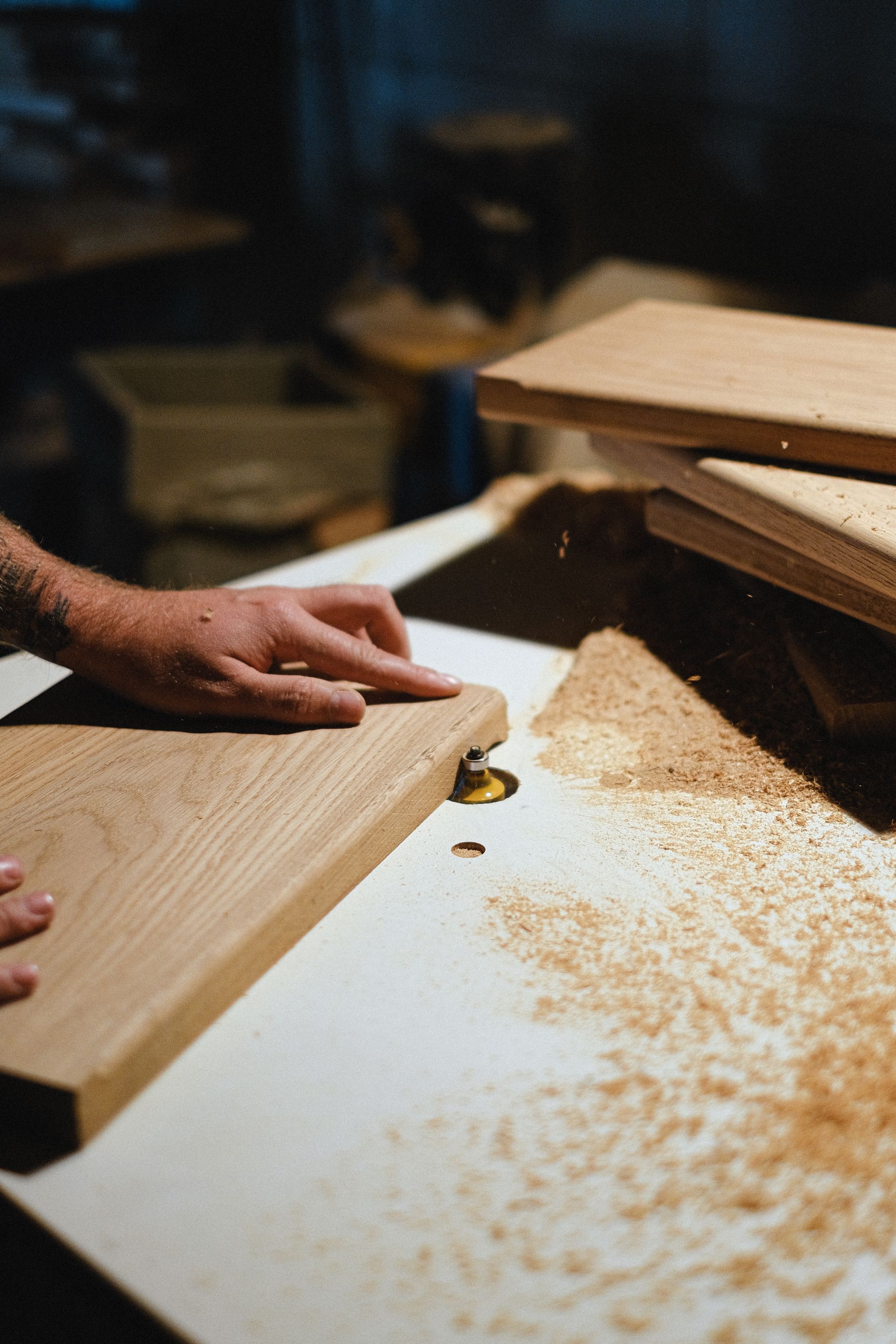 Hands resting on a freshly planed oak board covered in shavings.