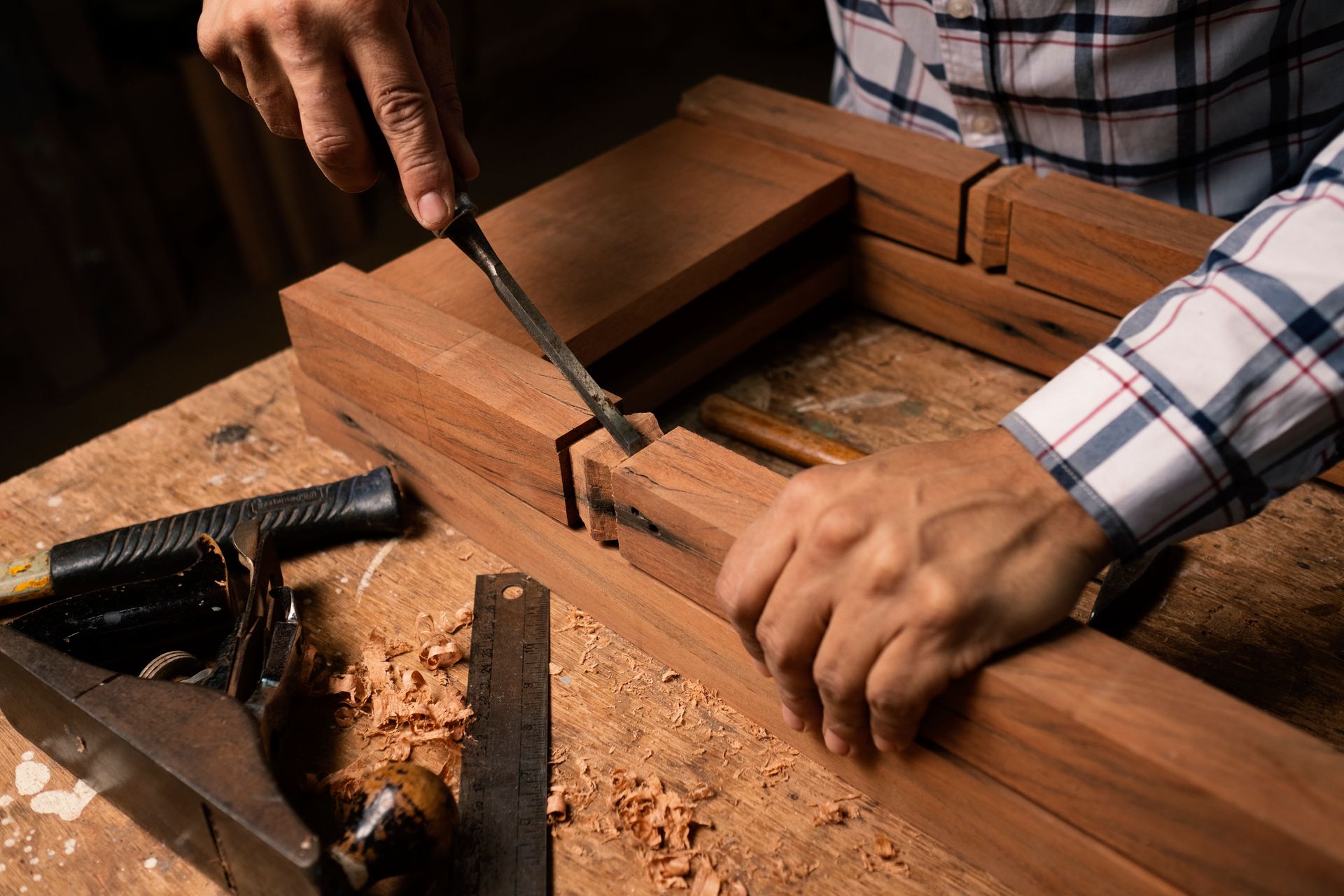 A cabinetmaker's hands paring a joint with a chisel.